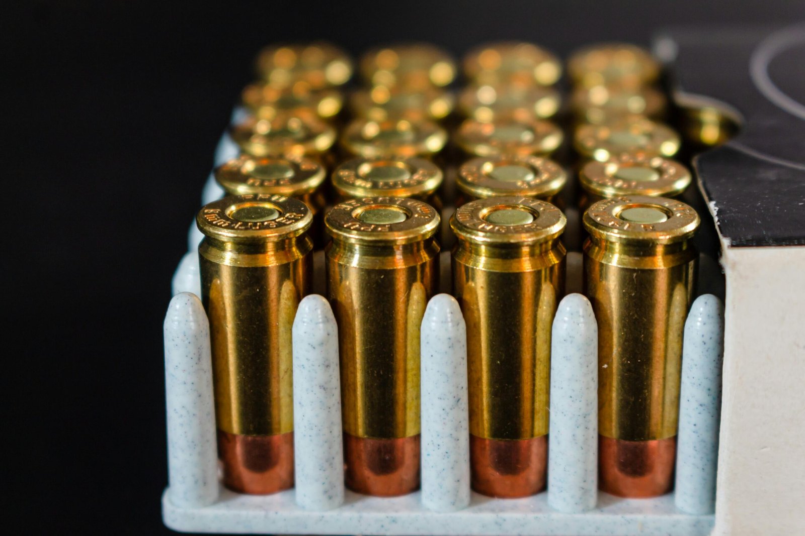 Detailed view of ammunition bullets neatly arranged in a box, showcasing brass casings and copper tips.