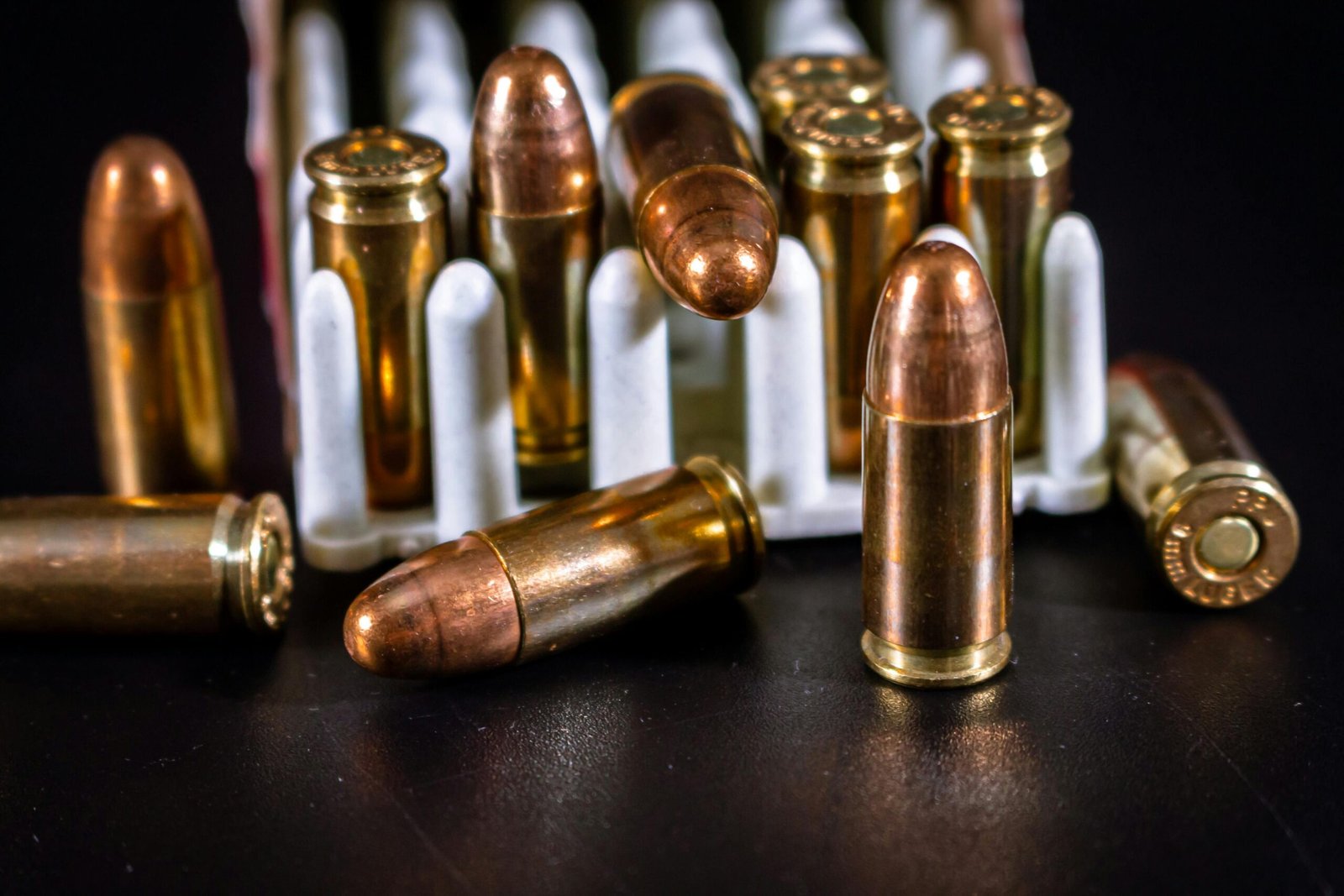 Detailed close-up of bullets arranged on a black surface, showcasing ammunition and brass casings.